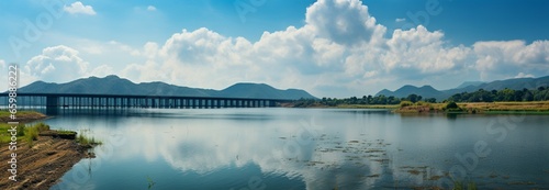 Natures spectacle: panoramic view of a serene dam, majestic mountains, and sky