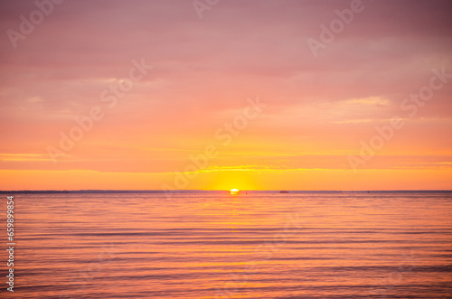 Beautiful bright picturesque dawn  sunrise on a river or sea in summer  through of clouds in the sky rays of red and orange color
