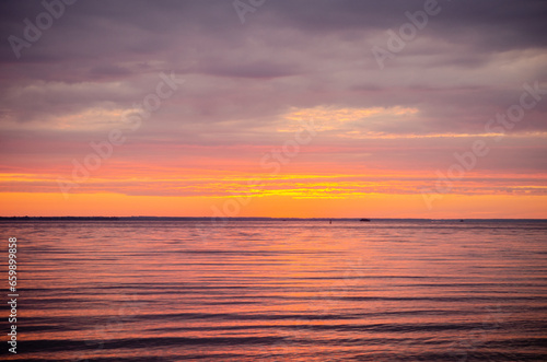 Beautiful bright picturesque dawn  sunrise on a river or sea in summer  through of clouds in the sky rays of red and orange color