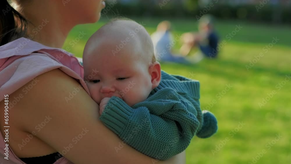 Mother holding her newborn baby in her arms in the park on a sunny day Mother holding her newborn baby in her arms in the park on a sunny day