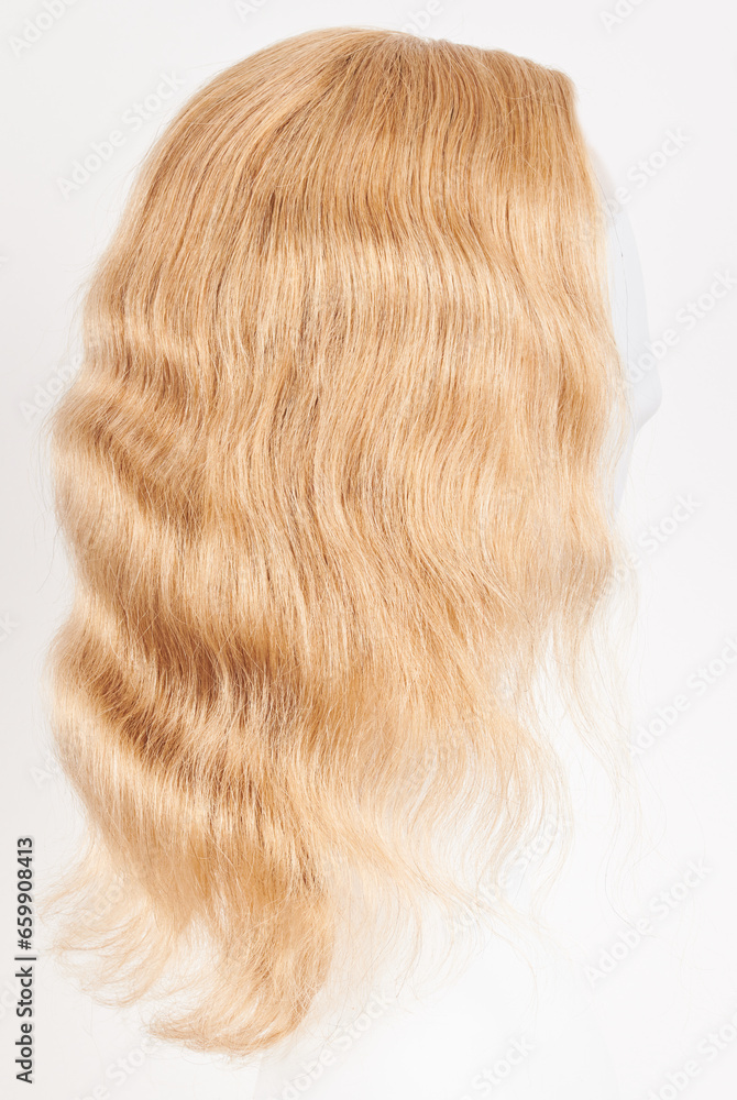 Naklejka premium Natural looking blonde wig on white mannequin head. Long hair on the plastic wig holder isolated on white background, side view.