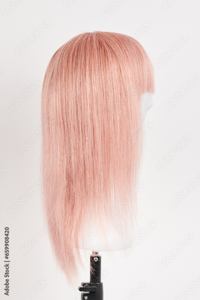 Natural looking pink blonde wig on white mannequin head. Long hair cut on the plastic wig holder isolated on white background Natural looking pink blonde wig on white mannequin head. Long hair cut on the plastic wig holder isolated on white background