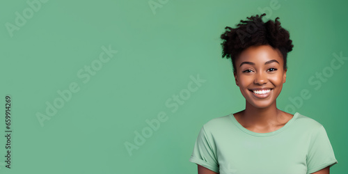 Smimilg young woman with dark skin and short groomed hair isolated on flat green pastel background with copy space. Model for banner of cosmetic products, beauty salon and dentistry