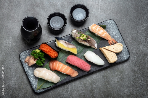 omakase mixed sushi set with sake on grey background photo