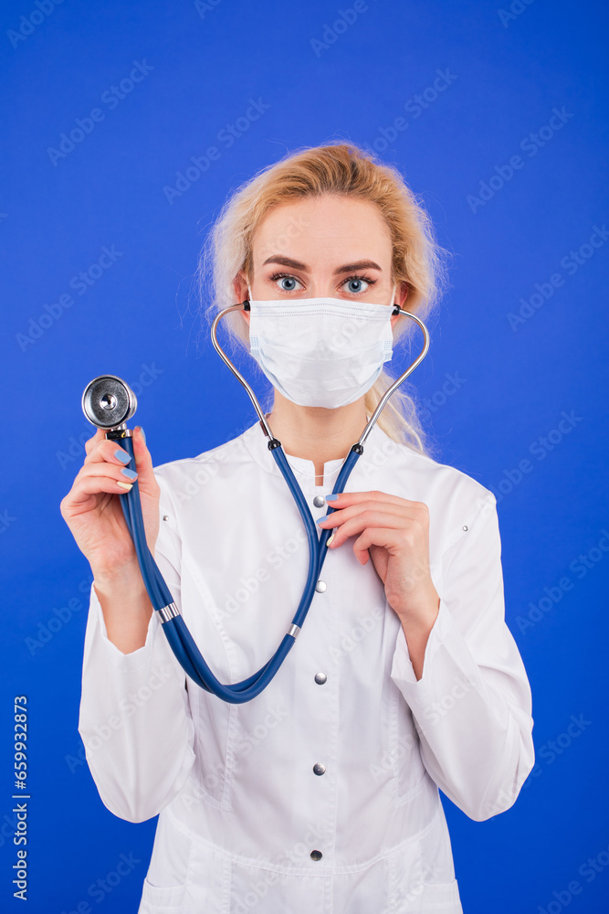 Portrait of a female doctor in a protective mask on a blue background. Portrait of a female doctor in a protective mask on a blue background.