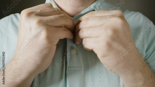 Male hands fasten buttons on a blue polo shirt