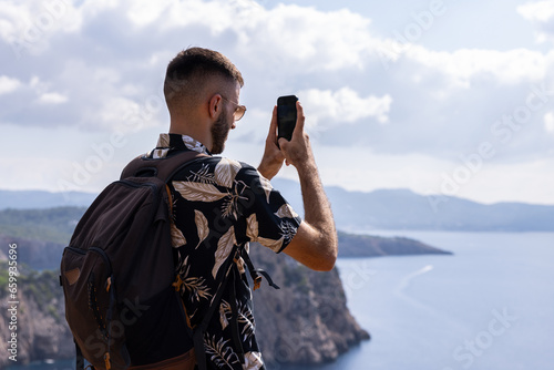 Caucasian man with short hair on a viewpoint doing a video with his mobile phone. High angle view