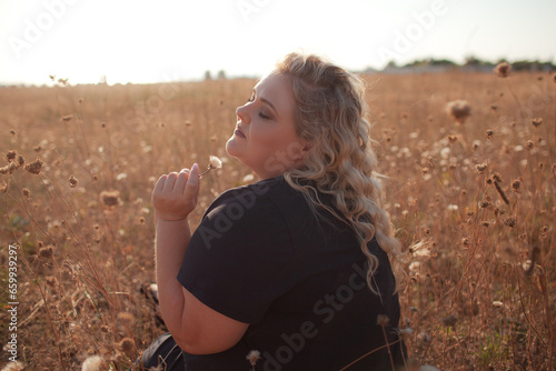 Portrait of beutiful plus size woman walks outdoor against the field and sunloght photo