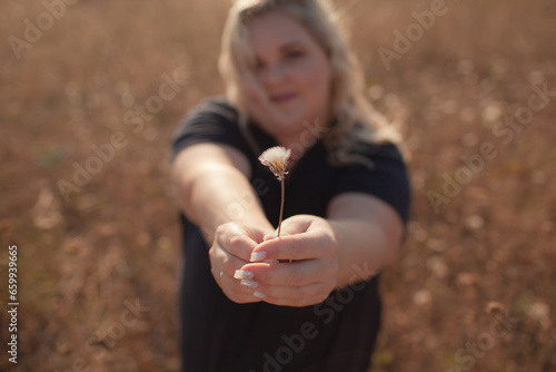 Portrait of beutiful plus size woman walks outdoor against the field and sunloght photo