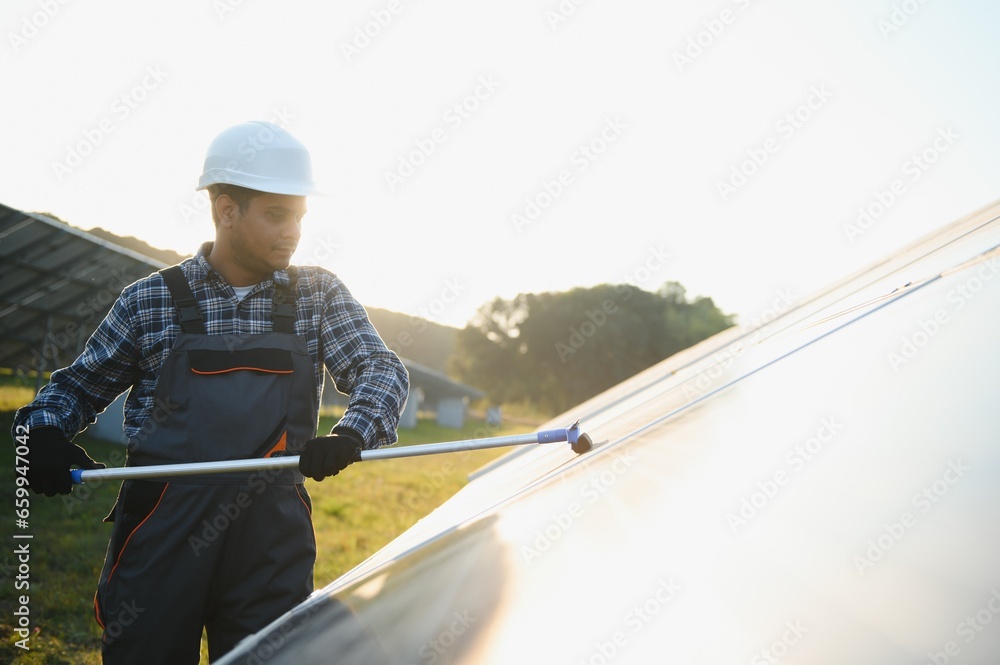 Indian handyman cleaning solar panels form dust and dirt Indian handyman cleaning solar panels form dust and dirt