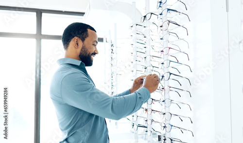 Optometry store glasses and man for decision, choice and eye care options for vision. Healthcare, ophthalmology and person in clinic to choose prescription lens, spectacles and frames for wellness