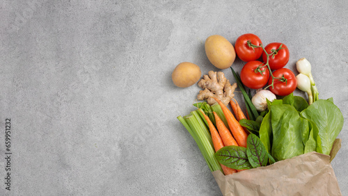 Paper bag with vegetables on a gray background. Healthy food delivery background, top view. Autumn harvest.