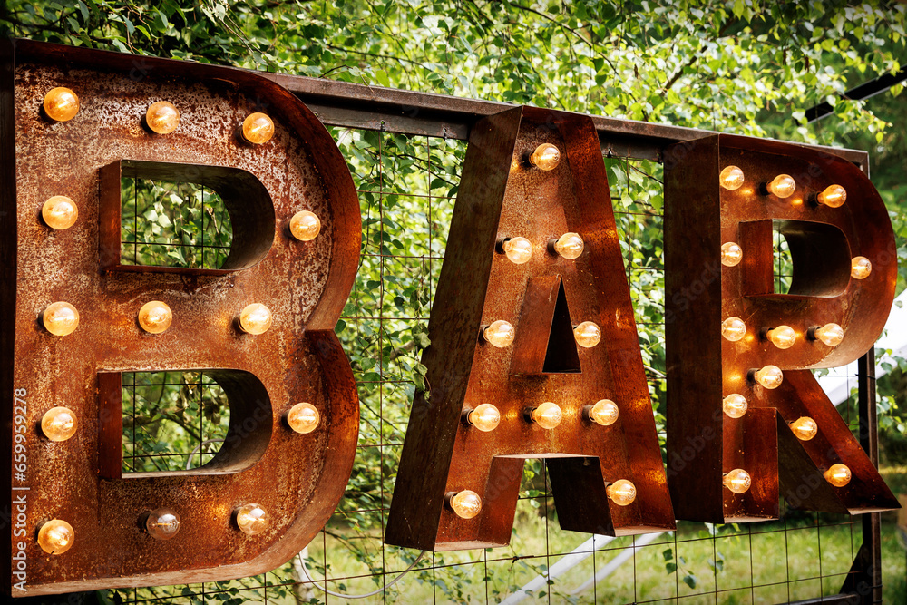Bar signboard. Inscription from large metal letters decorated with glowing light bulbs. - obrazy, fototapety, plakaty 