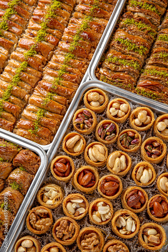 Different types of freshly baked baklava in baking trays. Turkish desert with peanut, pistachio for holiday or ramadan. Traditional Middle Eastern Flavors. Selective focus, pattern.