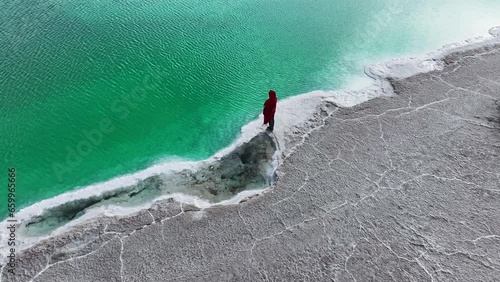 A woman in red dress standing at the Great Chaidan Emerald Lake in Qinghai province, China.