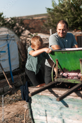 a little boy is busy processing grapes. happy father watching the process