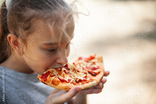 a girl eats pizza with appetite in nature on a summer day