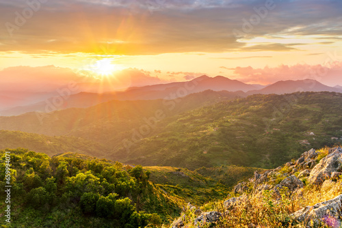 highland mountain landscape of beautiful sunset or sunrise with nice mountain peaks and slopes  green and golden hills and majestic cloudy sky on background