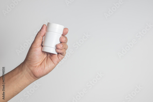 The man's hand held a medicine bottle containing antibiotics against a white background.