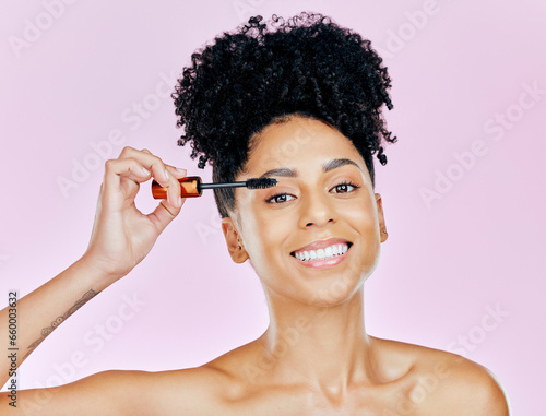 Portrait, smile and mascara with a woman on a pink background in studio to apply makeup or cosmetics. Beauty, skincare and face product with a happy young model on color for eyelash cosmetology