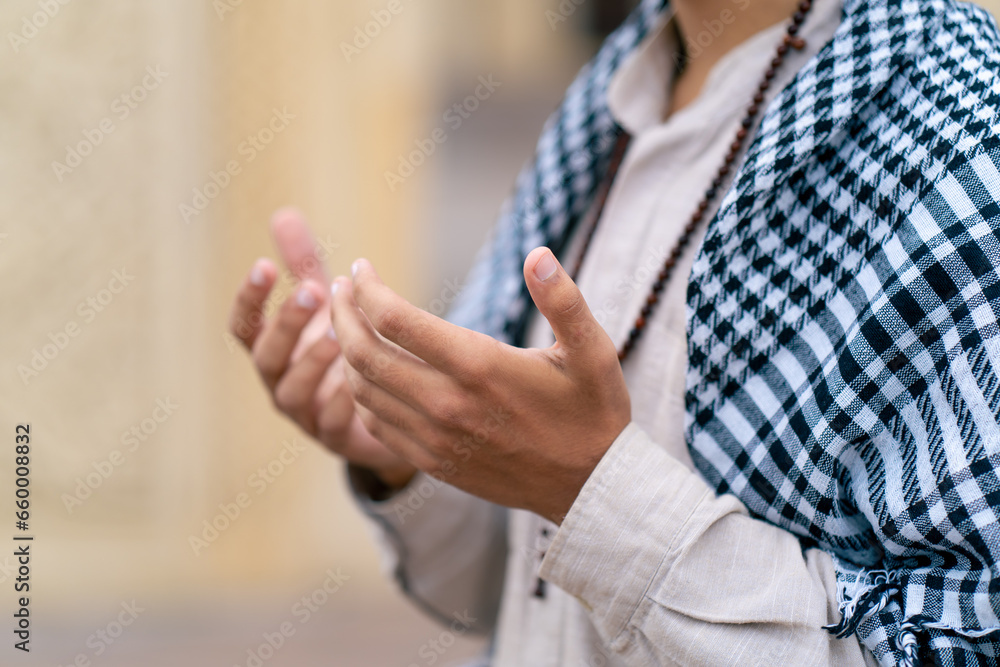 Close-up shot of the rosary and hands of an Arab man praying in the courtyard of Muslim mosque
