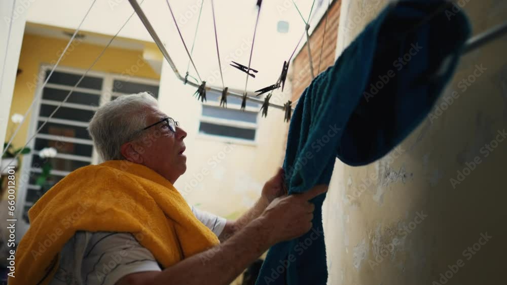 Senior Citizen Tending to Laundry in Backyard, retired Individual Handling Towels in Suburban residence, domestic lifestyle Senior Citizen Tending to Laundry in Backyard, retired Individual Handling Towels in Suburban residence, domestic lifestyle