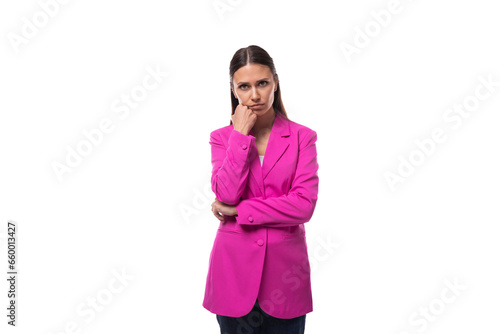 young smart office worker woman with black hair dressed in a pink jacket stands thoughtfully