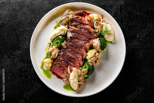 Cooked sliced beef steak rare with green broccoli.
