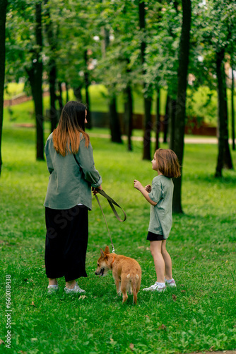family young mother walking in the park with her daughter and red dog relaxing in nature happy childhood love for animals