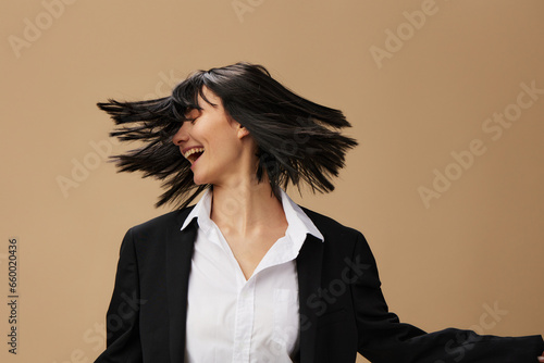 Happy dancing adorable brunet lady in classic suit throws head with flying hair posing isolated on pastel beige studio background. Copy space Banner Offer. Pulp Fiction concept. Fashion Cinema