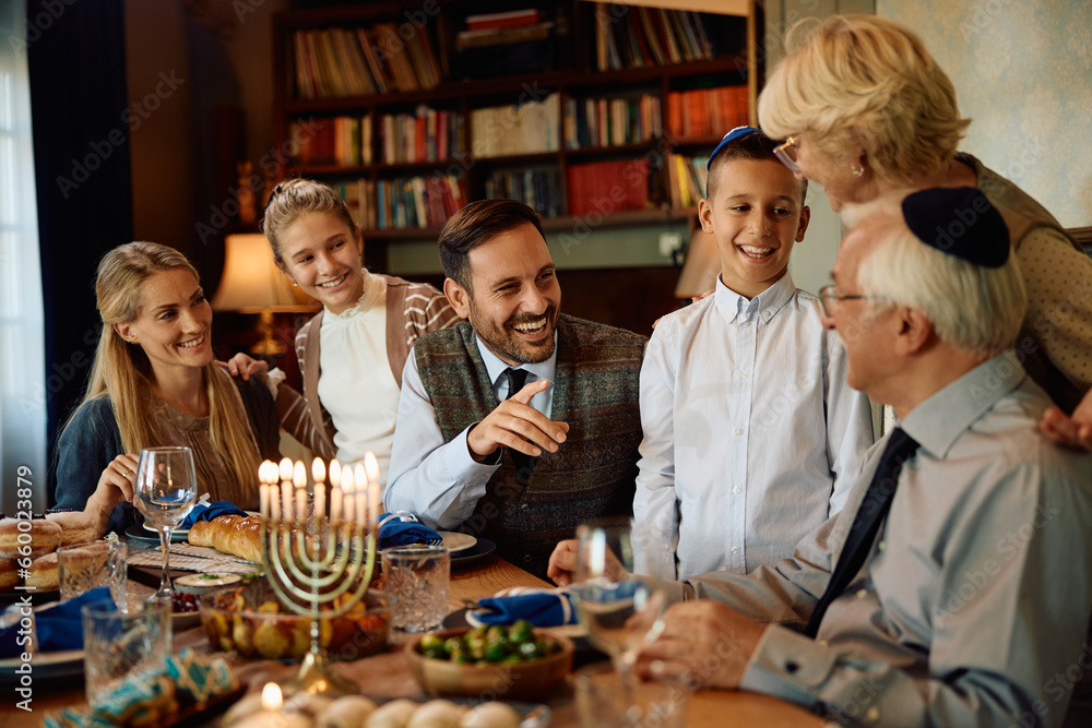 Happy Jewish extended family enjoys while gathering on Hanukkah at dining table.