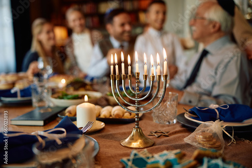 Canvas Print Lit candles in menorah with Jewish multigeneration family gathered for Hanukkah celebration
