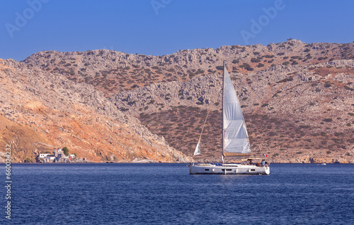 White yacht against the backdrop of high mountains in the bay of Symi island.