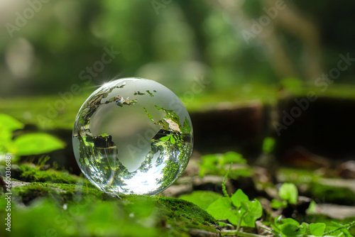 Concept of the Environment World Earth Day. Crystal globe putting on moss with sunlight  World sustainable environment. Saving the environment  and being environmentally sustainable. Save Earth