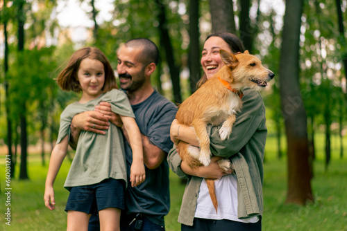 portrait happy young family in park with dog dad holding daughter in arms concept of trust care and family values