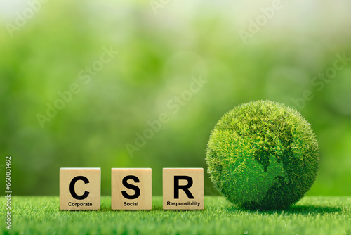 CSR (coporate social responsibility). words CSR on a woodblock and green world on a green background It is an idea for Corporate social responsibility and society activity concept.
