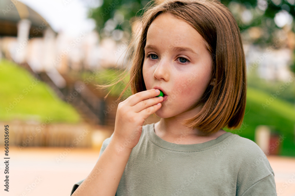 Fototapeta premium portrait beautiful cute girl eating small candies in the city park happy carefree childhood