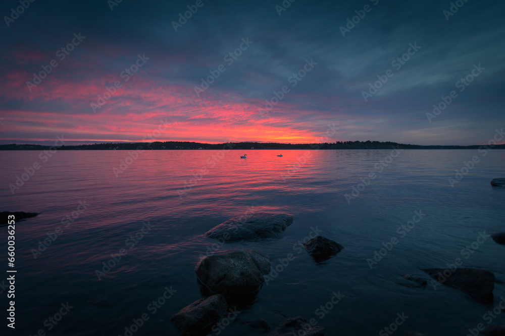 Landscape sunset with pink horizon and dark grey clouds over water with rocks in Stockholm.. Original public domain image from Wikimedia Commons Landscape sunset with pink horizon and dark grey clouds over water with rocks in Stockholm.. Original public domain image from Wikimedia Commons