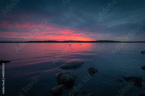 Photography Landscape sunset with pink horizon and dark grey clouds over water with rocks in Stockholm