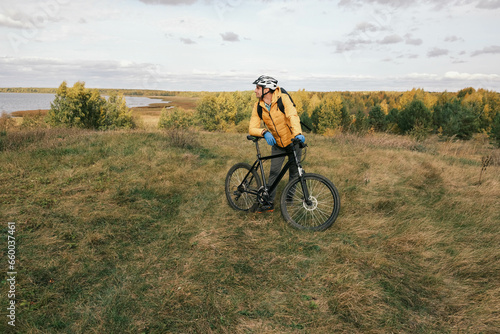 active lifestyle.A cyclist in a protective helmet with a backpack stands with a mountain bike in the autumn forest.Mountain Bike