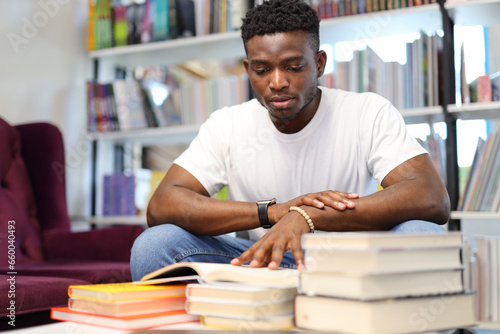 A serious young student in a university library, engrossed in his books, pursuing knowledge diligently.