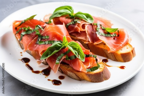 prosciutto bruschetta garnished with basil leaves on a white plate