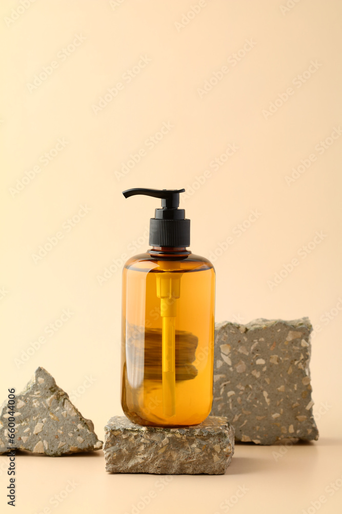 Yellow amber glass pump bottle design for natural cosmetics shampoo or shower gel on stone pedestal.