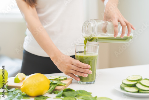Detox juice concept, Hand of woman, girl holding bottle making green vegetable smoothie pouring in glass for diet at home kitchen, drinking healthy meal food for weight loss. Lifestyle vegan nutrition