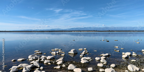 Embalse de Valdecañas, Caceres. Toma del horizonte con las montaña y el agua todo en azul, y al principio la orilla con piedras blancas