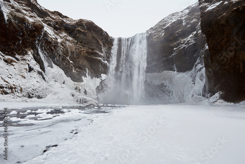 Breathtaking winter scene in Iceland with a magnificent waterfall, snow-covered landscape