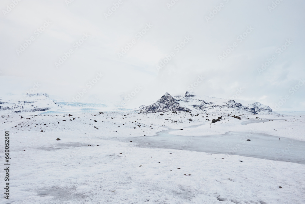 A mesmerizing Icelandic landscape showcasing a blue lagoon, vast frozen lake, snow-covered mountains