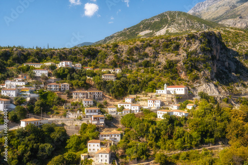 View of white houses with yellow shutters, moutains and sea. Vuno, Albania.