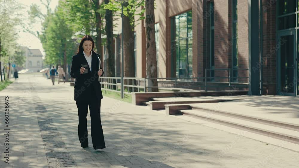 Happy smiled business woman wearing formal suit going to the business centre holding her laptop for work and holding eco cup for coffe or tea. People and technology concept Happy smiled business woman wearing formal suit going to the business centre holding her laptop for work and holding eco cup for coffe or tea. People and technology concept