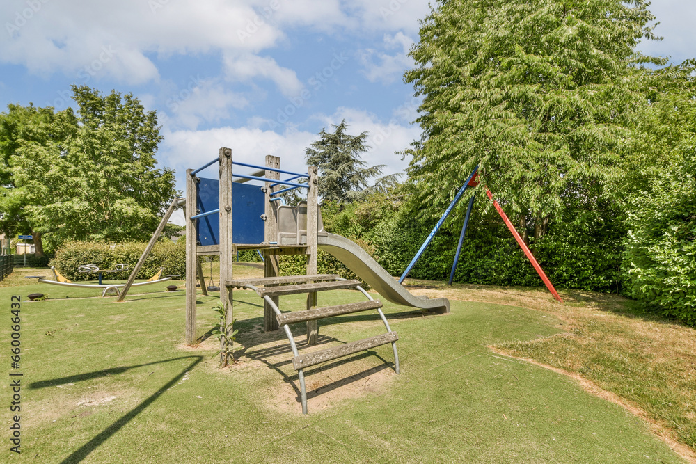 Fototapeta premium a playground with swings, slides and slides in the grass area next to some trees on a sunny day
